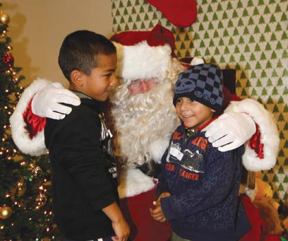 Joe Jacobson Two young boys receive presents from Santa at Infineon’s ‘Race to the Holidays’ party